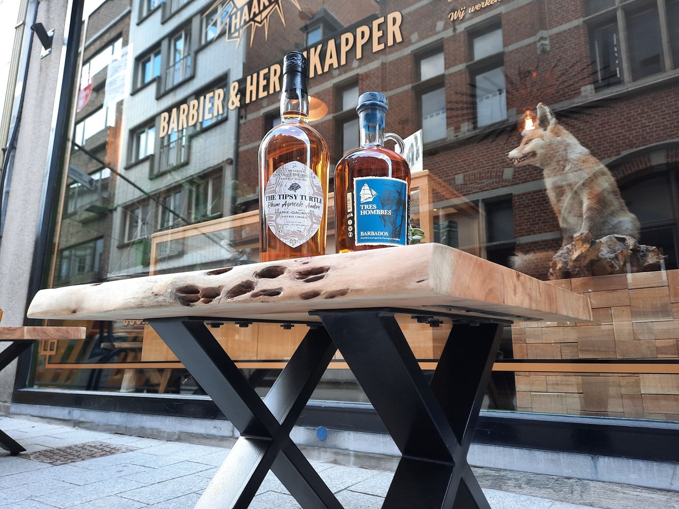 De gevel van Haartiest, barbier en herenkapper, met whisky op een tafel voor de deur